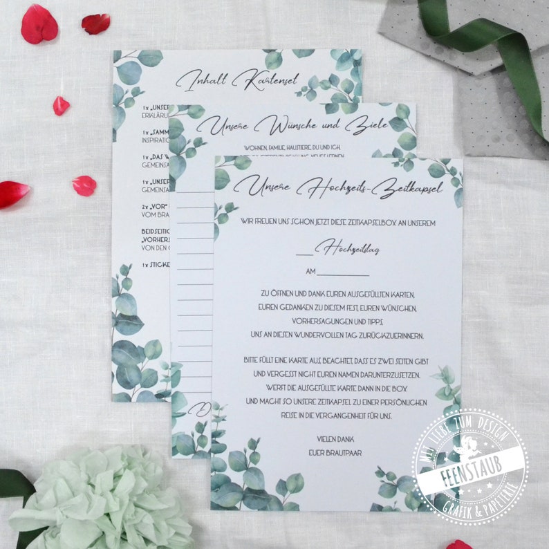 May include: A white card with a green eucalyptus leaf design. The card has the text "Our Wedding Time Capsule" and instructions for filling out the cards. The text also says "We are excited to open this time capsule on our wedding day."