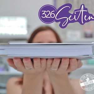 Puede incluir: Una persona sosteniendo un libro grande, blanco y encuadernado con una encuadernaci&oacute;n plateada. El libro est&aacute; titulado "326 Seiten" en texto morado. El libro se sostiene frente a la cara de una persona, con el lomo del libro mirando hacia la c&aacute;mara.