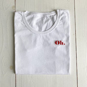 Könnte beinhalten: Weißes T-Shirt mit dem Wort "Oh." in roten Buchstaben auf der Vorderseite.
