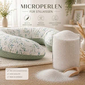 Puede incluir: Una almohada de lactancia en forma de U con un estampado floral en verde y blanco, junto a un recipiente de vidrio transparente lleno de pequeñas perlas blancas. También se ven una cuchara de madera y un montón de perlas. El texto de la imagen dice "MICROPERLEN FÜR STILLKISSEN".