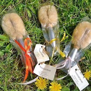 Könnte beinhalten: Drei Naturborsten-Nagelbürsten, verpackt in durchsichtigen Plastiktüten mit bunten Bändern. Jede Bürste hat einen silbernen Griff und ein Etikett mit der Aufschrift "Handgemacht aus Sisal, rostfreien Stahl und Holz", was "Handgefertigt aus Sisal, rostfreiem Stahl und Holz" bedeutet.