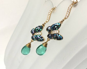 May include: Gold butterfly earrings with green teardrop stones. The butterflies are made of black and iridescent mosaic tiles and have clear rhinestones.