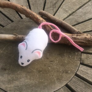 May include: White plush toy mouse with pink ears and a pink tail. The mouse has embroidered eyes and a nose.