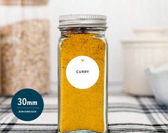 May include: A clear glass spice jar filled with yellow curry powder. The jar has a silver lid and a white label with the word "CURRY" and a small gold heart. The jar is approximately 30mm in diameter.