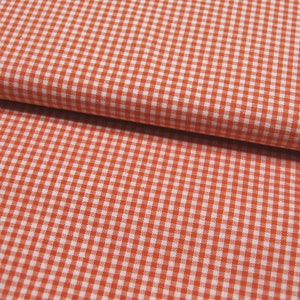 Könnte beinhalten: Orangefarbener und weißer Gingham-Stoff mit kleinem Karomuster.