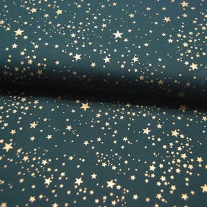Op de afbeelding: Teal stof met een verspreid patroon van gouden sterren in verschillende maten.