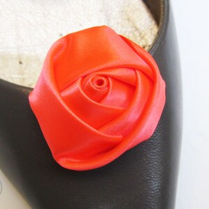 Pu&ograve; includere: Un ornamento per scarpe a forma di rosa in raso arancione brillante. La rosa &egrave; realizzata in tessuto e ha un aspetto realistico.