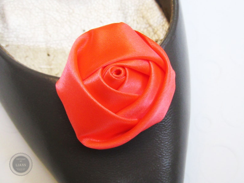 Pu&ograve; includere: Un ornamento per scarpe a forma di rosa in raso arancione brillante. La rosa &egrave; realizzata in tessuto e ha un aspetto realistico.