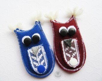 Könnte beinhalten: Zwei Filz-Fingerpuppen in Form von Eulen, eine blaue mit weißer Spitze und schwarzen Augen, die andere rot mit weißer Spitze und schwarzen Augen.