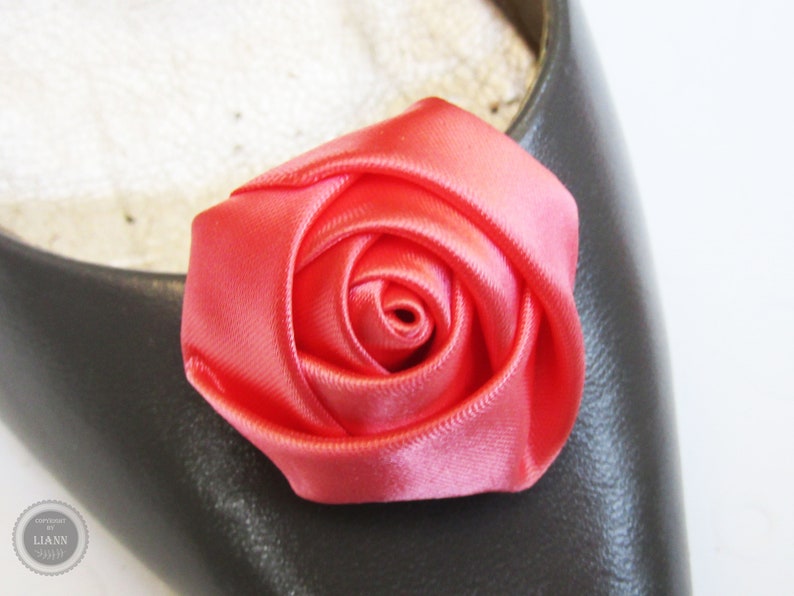 Pu&ograve; includere: Un fiocco di rosa in raso rosa brillante. La rosa &egrave; fatta di tessuto ed &egrave; un unico fiore.