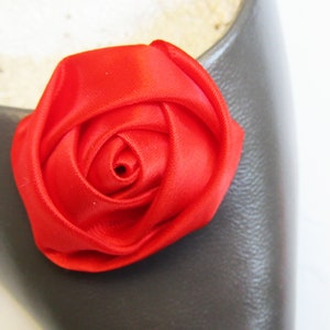Pu&ograve; includere: Un fiocco di fiore di rosa in raso rosso brillante. La rosa &egrave; fatta di tessuto ed &egrave; un unico fiore.