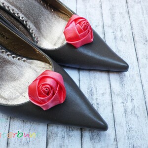 Pu&ograve; includere: Due ballerine grigie con decorazioni di rose in raso rosa sulle dita.