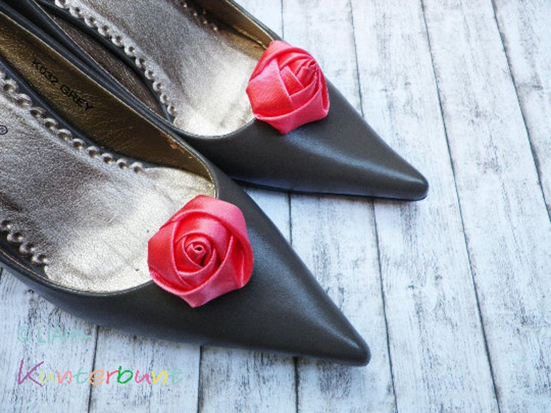 Pu&ograve; includere: Due ballerine grigie con decorazioni di rose in raso rosa sulle dita.