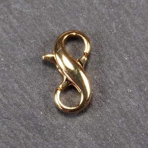 Puede incluir: Cierre de langosta de metal dorado con diseño de símbolo de infinito.