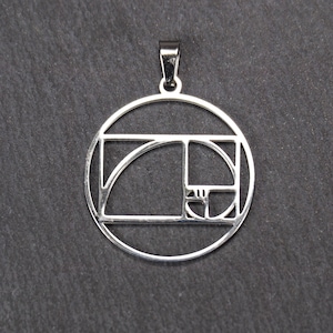 Könnte beinhalten: Silberner Anhänger mit einer runden Form und einem geometrischen Muster, das von der Fibonacci-Folge, auch bekannt als der Goldenen Schnitt, inspiriert ist.