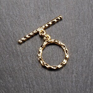May include: Gold-toned metal toggle clasp with a textured, round ring. The clasp is designed for jewellery making and features a sturdy, secure closure.