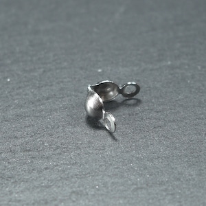 May include: Silver metal bead cap with a rounded end and a small loop on each side.