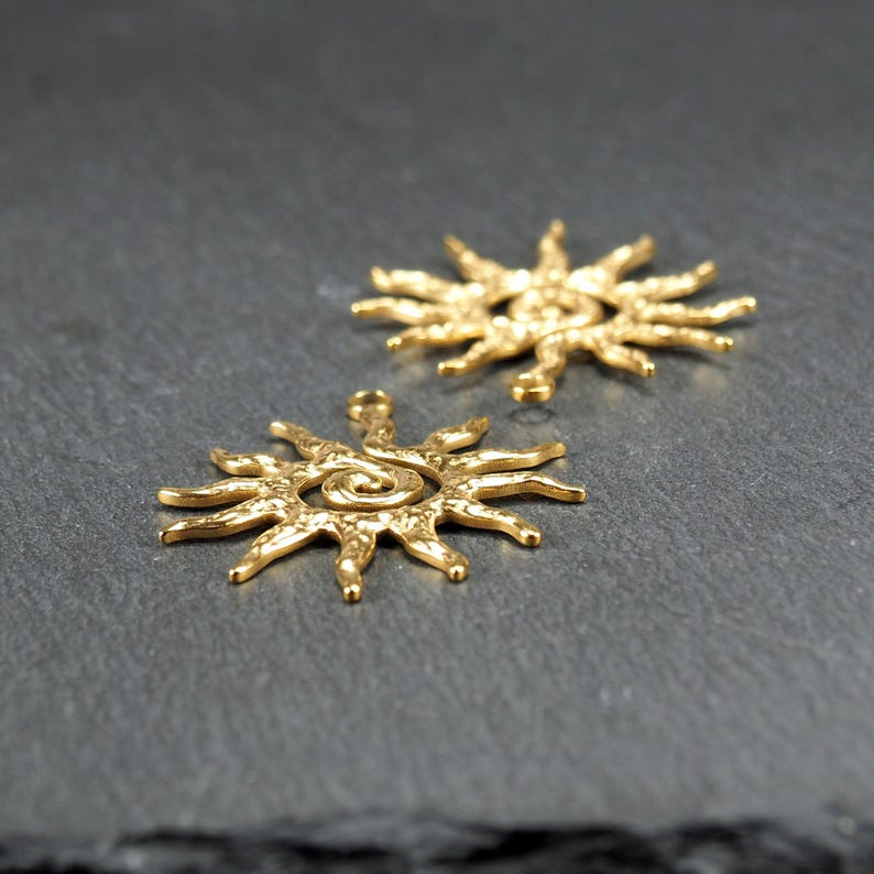 May include: Two gold-toned metal sun charms with a spiral design in the center. The charms have a textured surface and are perfect for jewelry making.