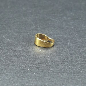 May include: A gold-coloured metal pendant bail with a smooth, rounded surface.