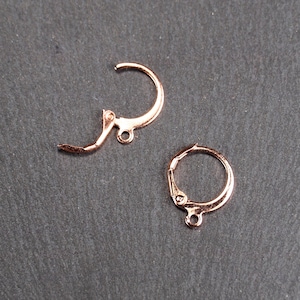 Peut inclure: Deux crochets d'oreille en or rose. Un crochet est un simple cercle, l'autre est un crochet incurvé avec une petite boucle à l'extrémité.