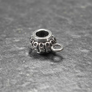 May include: Silver-toned metal bead with a decorative design and a small loop. The bead is designed to be used as a spacer or charm for jewellery making.