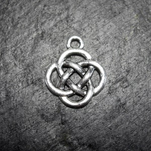 Puede incluir: Encanto de nudo celta de plata con un diseño de trébol de cuatro hojas.