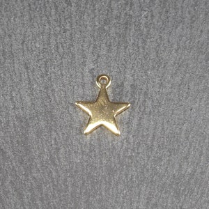 May include: A gold-coloured metal star charm with a loop at the top for attaching to jewellery or other crafts.
