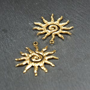 May include: Two gold-toned metal sun charms with a spiral design in the center. The charms have a textured surface and are perfect for jewelry making.