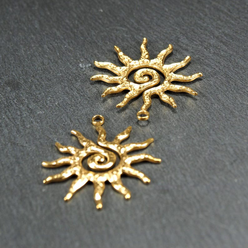 May include: Two gold-toned metal sun charms with a spiral design in the center. The charms have a textured surface and are perfect for jewelry making.