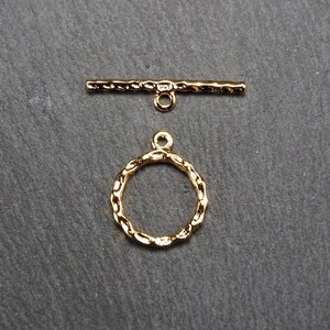 May include: Gold-toned metal toggle clasp with a round, textured ring. The clasp is designed for jewellery making and crafting.