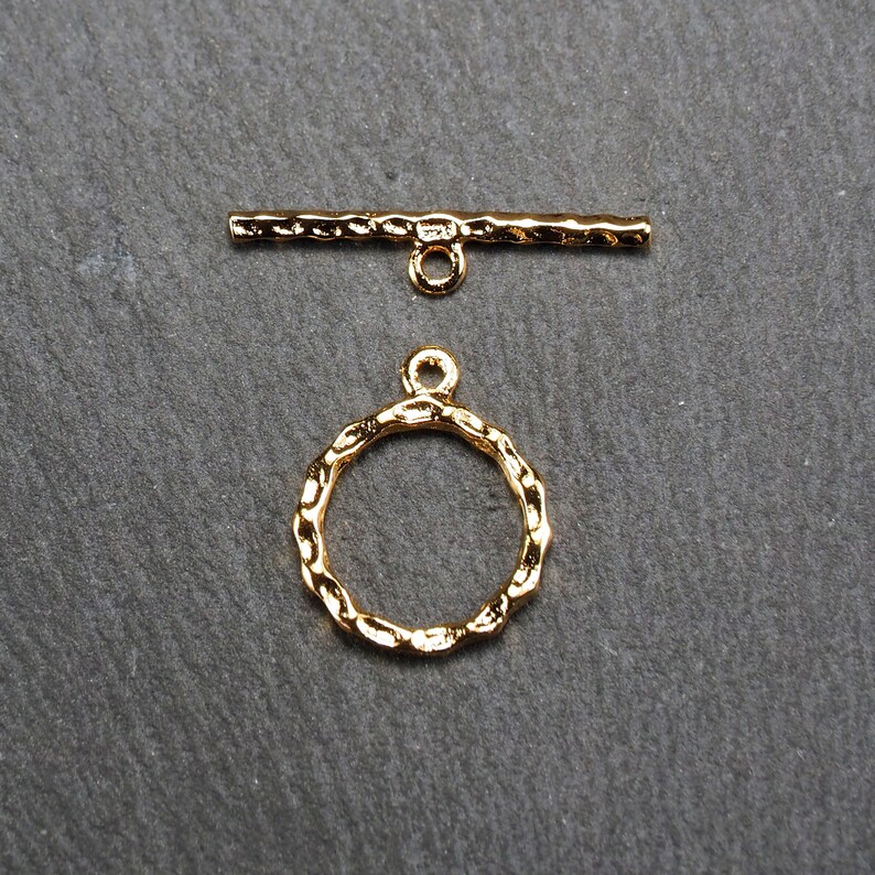 May include: Gold-toned metal toggle clasp with a round, textured ring. The clasp is designed for jewellery making and crafting.