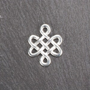 Puede incluir: Encanto de plata con un diseño de nudo celta. El nudo es un símbolo tradicional de amor, amistad y eternidad.