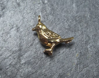May include: A gold-colored bird charm pendant. The bird is depicted in a realistic style with detailed feathers and a small beak.