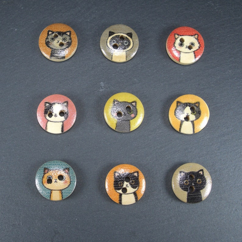 Puede incluir: Nueve botones coloridos con diferentes dise&ntilde;os de gatos. Los botones son redondos y tienen un fondo blanco con contornos negros. Los gatos son todos de diferentes colores y tienen diferentes expresiones.