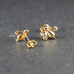 May include: A pair of gold bee stud earrings. The bees are detailed with textured wings and bodies.