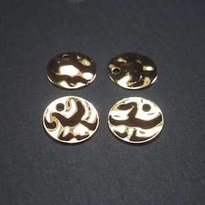 Może przedstawiać: Cztery złote metalowe dyski o fakturowanej powierzchni. Dwa z dysków mają prosty wzór, a dwa pozostałe mają bardziej skomplikowany wzór.