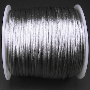 May include: A spool of silver satin cord.