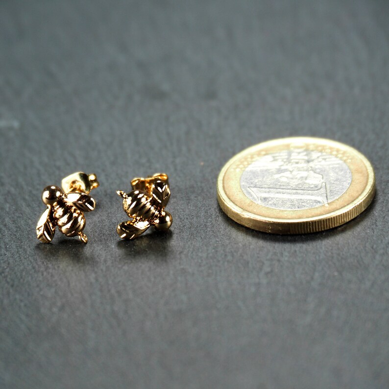 May include: A pair of gold bee stud earrings. The earrings are small and delicate, and they would make a great gift for someone who loves bees.