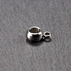 May include: A silver-toned metal bead with a small loop on the side. The bead is round and has a smooth surface.
