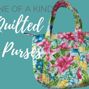 Op de afbeelding: Gewatteerde handtas met een bloemenpatroon in roze, blauw en geel. De tote bag heeft een gewatteerd ontwerp en een voorvak. De tekst "ONE OF A KIND Quilted Purses" staat op de afbeelding.