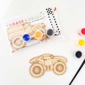 May include: A wooden monster truck craft kit with paint pots in black, blue, yellow, and red. The kit includes a paintbrush and a card that says "Smash & Crash my birthday bash!"