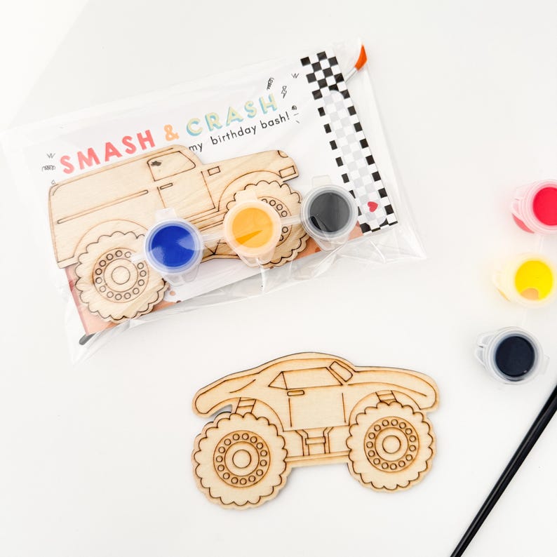 May include: A wooden monster truck craft kit with paint pots in black, blue, yellow, and red. The kit includes a paintbrush and a card that says "Smash & Crash my birthday bash!"