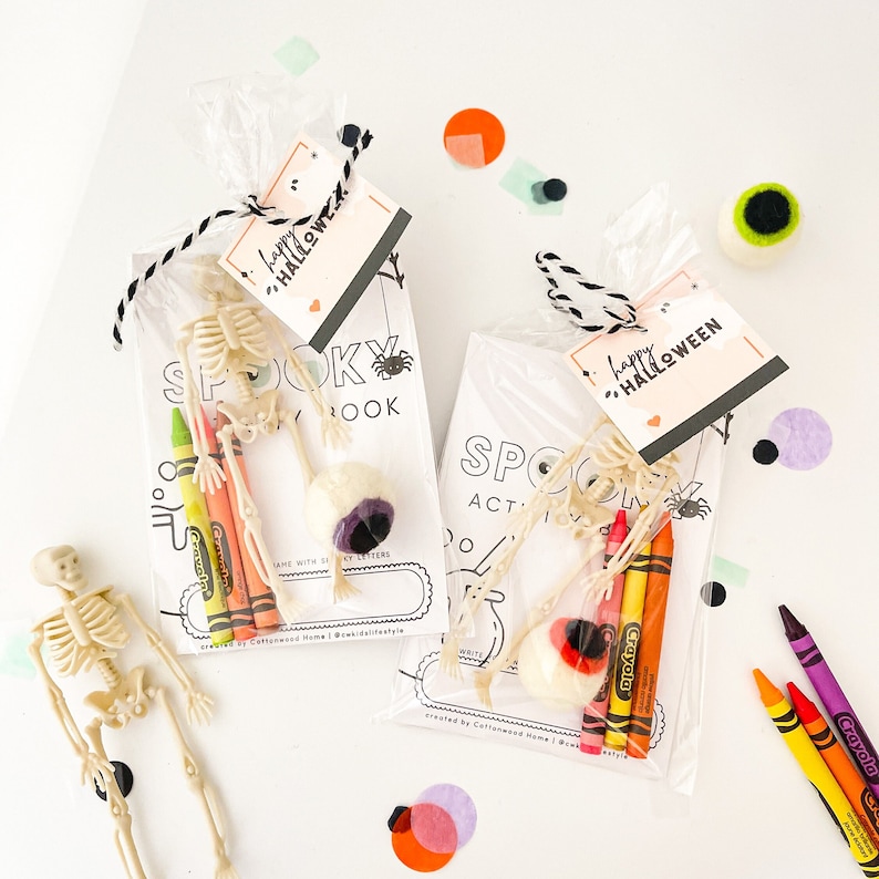 May include: Two clear plastic favor bags containing a Spooky Activity Book, a plastic skeleton, three Crayola crayons in yellow, orange, and red, and a felt eyeball. Each bag is tied with black and white twine and a Happy Halloween gift tag.