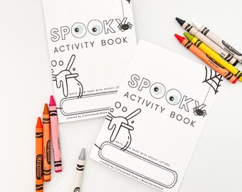 May include: Two white activity books titled SPOOKY ACTIVITY BOOK with black line art of a spider, web, and cauldron. The covers feature a blank space to write a name. Seven colorful Crayola crayons in orange, red, yellow, black, and white are included.