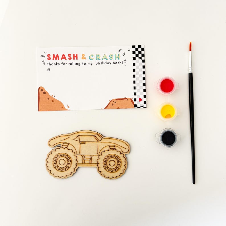 May include: A wooden monster truck cutout with a paint-by-numbers design. The kit includes three small paint pots in red, yellow, and black, and a paintbrush. The card reads "Smash & Crash thanks for rolling to my birthday bash!"