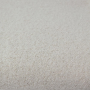 Könnte beinhalten: Nahaufnahme eines strukturierten, cremefarbenen Stoffes. Das Material hat eine weiche, leicht unebene Oberfläche mit einem dichten, faserigen Aussehen. Die Farbe ist ein gedämpfter, neutraler Ton, der auf ein natürliches oder ungefärbtes Textil hindeutet.