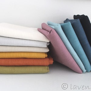 May include: A stack of fabric swatches in various colors, including white, beige, yellow, orange, green, blue, and pink. The swatches are arranged in a staggered pattern, with the white swatches on top and the pink swatches on the bottom.