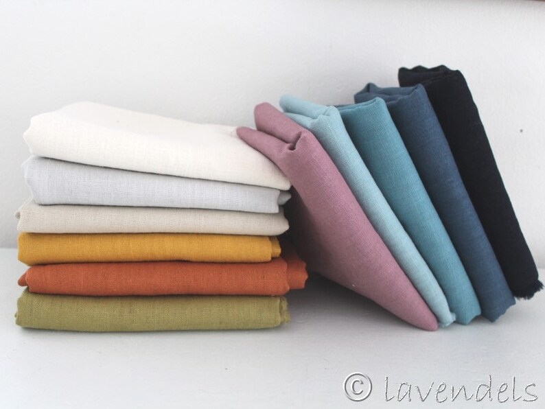 May include: A stack of fabric swatches in various colors, including white, beige, yellow, orange, green, blue, and pink. The swatches are arranged in a staggered pattern, with the white swatches on top and the pink swatches on the bottom.