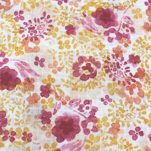 Peut inclure: Un tissu blanc avec un motif floral dans des tons de rose, orange et jaune. Les fleurs sont petites et délicates, et le tissu a une texture douce.