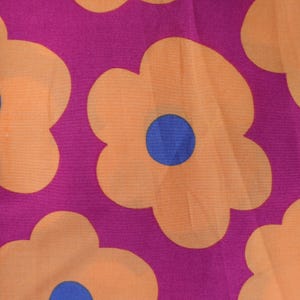 Może przedstawiać: Różowy materiał z powtarzającym się wzorem pomarańczowych kwiatów z niebieskimi środkami.